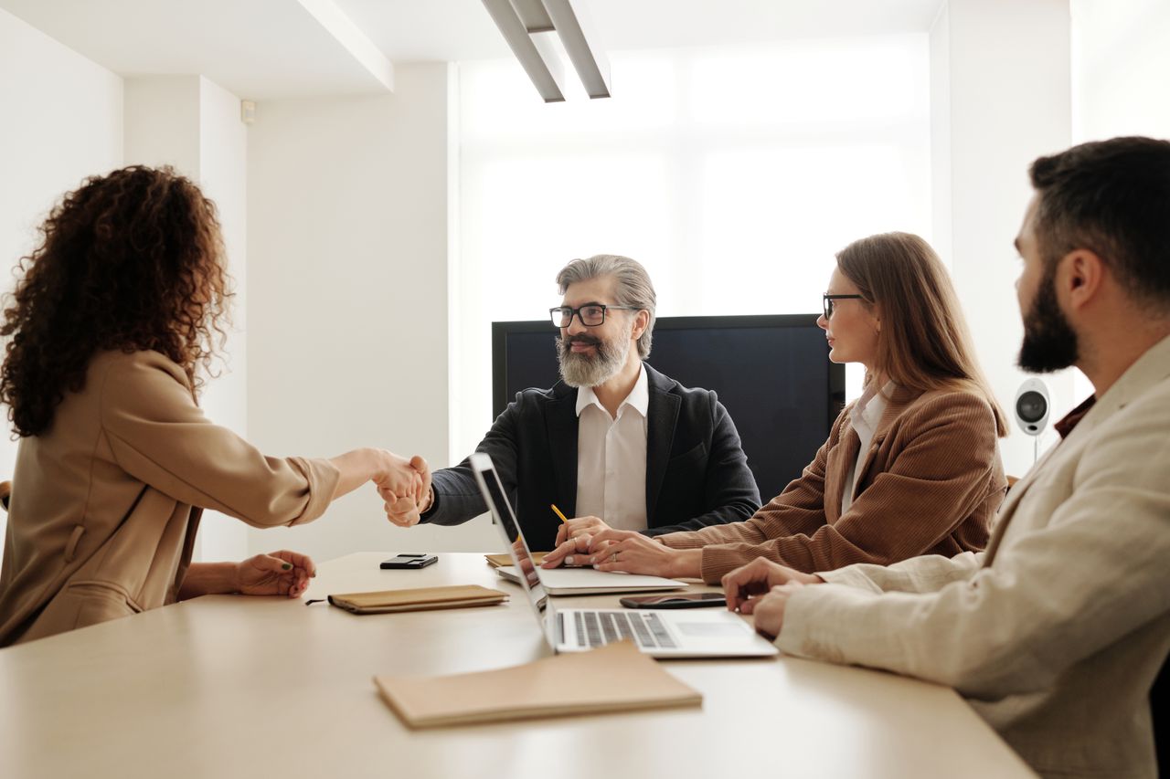 Home Faceless coworkers in formal clothes shaking hands during meeting at work in light office